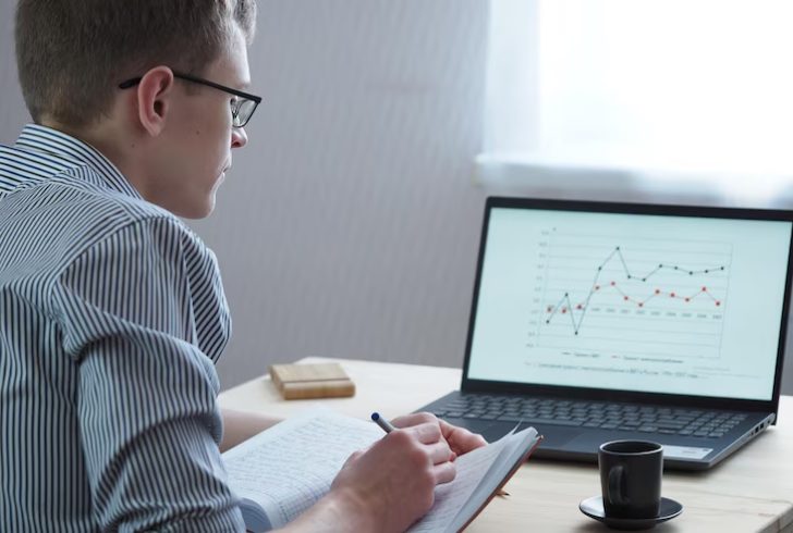 A person highlighting graphs or charts on notepad