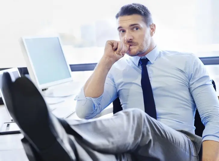 Shot of a nervous-looking businessman sitting with his feet up on his desk