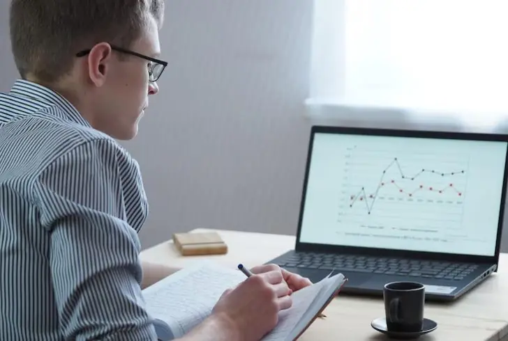 A person highlighting graphs or charts on notepad